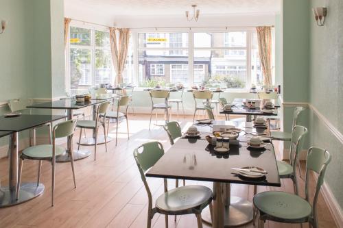 uma sala de jantar com mesas, cadeiras e janelas em Braemar em Shanklin