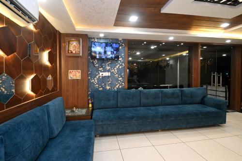 a lobby with a blue couch and a tv at Hotel Hallmark By THC Group in Kota
