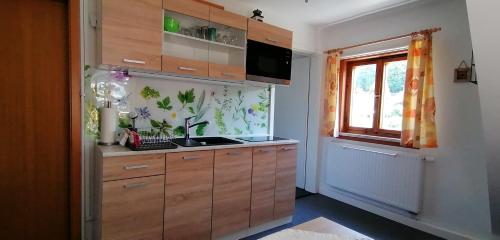 una cocina con armarios de madera y una ventana en Ferienwohnung Müller, en Steinach