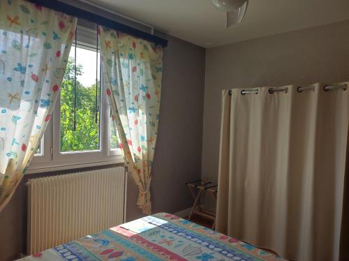 a bedroom with a bed and a window with curtains at Chez Colombine in Chaponost