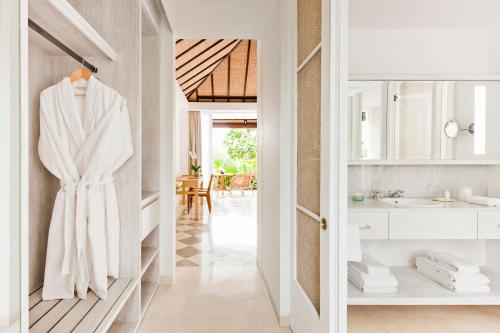La salle de bains est pourvue d'un peignoir blanc suspendu à un placard. dans l'établissement COMO Uma Ubud, à Ubud