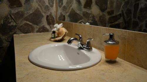 un lavabo de baño con una bebida naranja junto a él en Villa Creole en Jacó