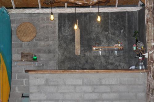 a bathroom with a stone wall with a sink and lights at Jungle House - surf & stay in Pulukan