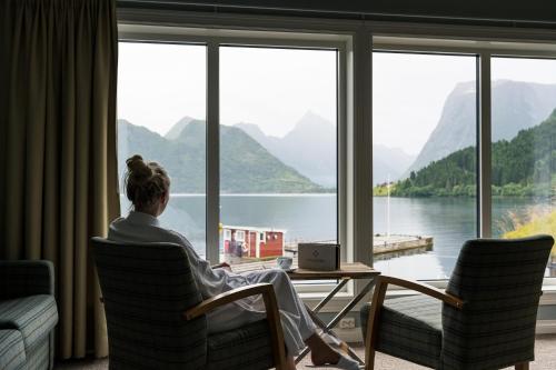 a woman sitting in a chair looking out a window at Sagafjord Hotel - by Classic Norway Hotels in Sæbø