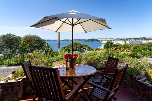 a table and chairs with an umbrella on a patio at The Old Coastguard Station, Sea Views & Courtyard in Falmouth
