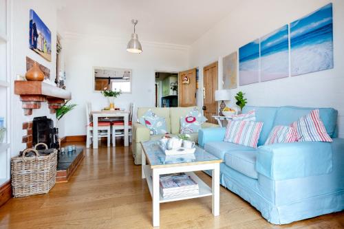 a living room with a blue couch and a table at The Old Coastguard Station, Sea Views & Courtyard in Falmouth