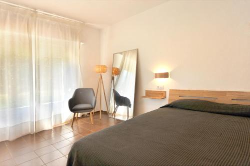 ein Schlafzimmer mit einem Bett und einem Stuhl und einem Fenster in der Unterkunft ROIG in Sant Martí d’Empúries