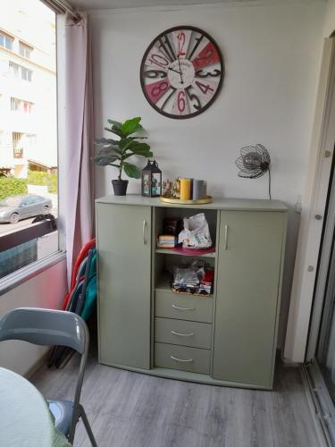 un meuble vert avec une horloge sur un mur dans l'établissement Studio cabine avec loggia, au Cap d'Agde