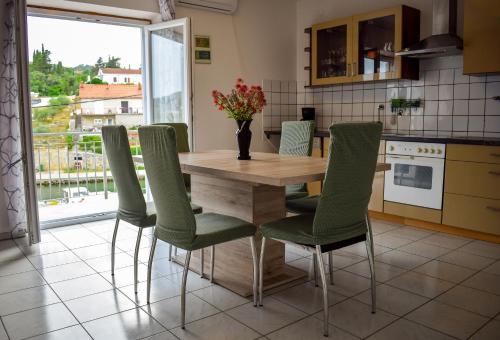 a kitchen with a wooden table and green chairs at Maslinčica in Veli Iž