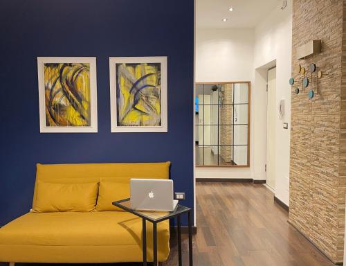 a yellow couch in a living room with a laptop on a table at Residence Petrone in Foggia