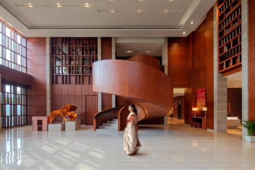 a woman walking through a lobby with a spiral staircase at Hyatt Regency Chandigarh in Chandīgarh