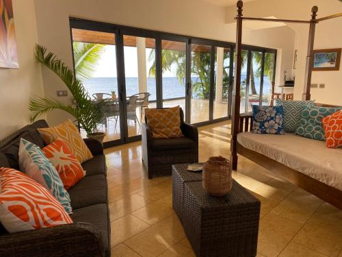 ein Wohnzimmer mit einem Sofa, Stühlen und Meerblick in der Unterkunft Ocean Breeze Villa in Tevaitoa