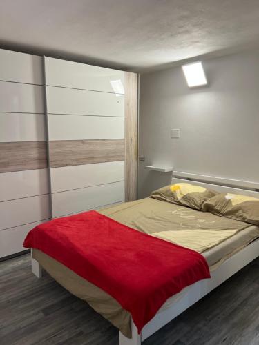 a bedroom with a bed with a red blanket on it at Apartma Ročica in Kobarid