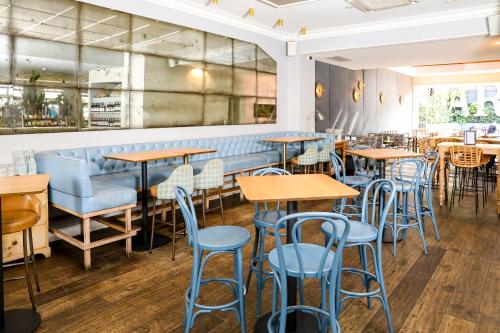 a restaurant with wooden tables and blue stools at Charing Cross Hotel in Sydney