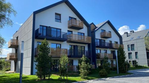 un edificio de apartamentos con balcones en una calle en Apartament Seaside Dune - Aleja Południowa 14A Dźwirzyno, en Dźwirzyno