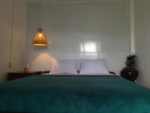 a bedroom with a bed with a green blanket and a lamp at Rinjani Houseboon in Senaru