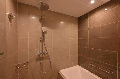 a bathroom with a shower and a bath tub at Ryukyu Hotel & Resort Nashiro Beach in Itoman