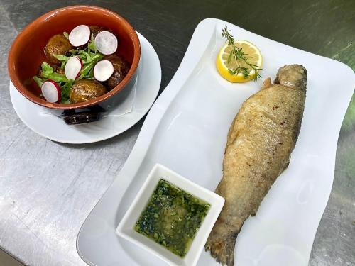 a white plate with a fish and a bowl of food at Hotel Zarja in Pohorje
