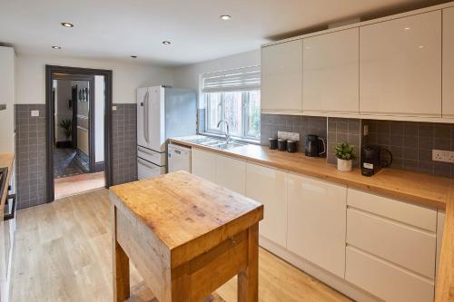 a kitchen with white cabinets and a wooden table at Host & Stay - Raven House in Robin Hood's Bay