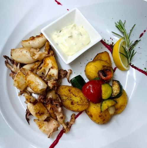 a plate of food with shrimp and vegetables and dipping sauce at Hotel Zarja in Pohorje