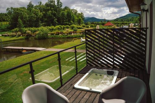 a balcony with a hot tub and chairs on a deck at Caryńska Resort & SPA in Lutowiska