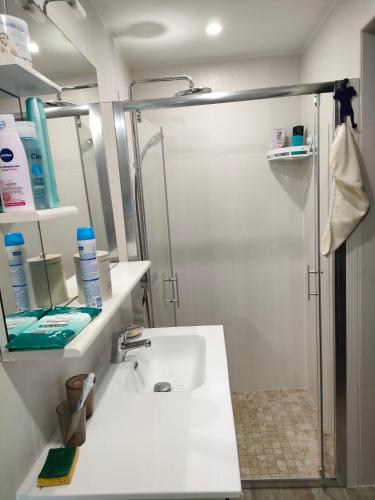 une salle de bain blanche avec un lavabo et une douche dans l'établissement CHEZ TINOU appartement T2 saisonnier, à Florensac