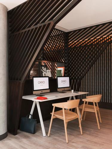 two computers sitting on a desk with two chairs at OKKO Hotels Paris La Défense in Nanterre