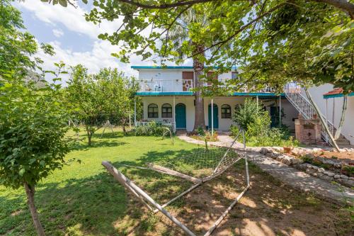 a house with a blue roof and a yard at Jasmin Pansiyon Çıralı in Cıralı