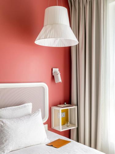 a bedroom with a white bed and a lamp at OKKO Hotels Paris La Défense in Nanterre