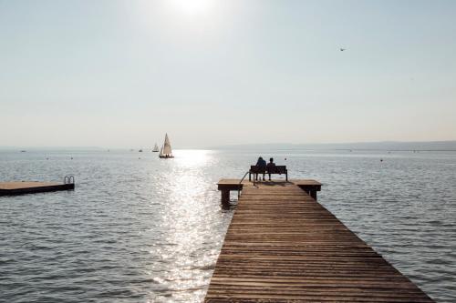 two people sitting on a bench on a pier over the water at Luis von Weyden in Weiden am See