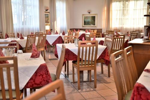 a restaurant with tables and chairs with red and white table cloth at Hotel Bel Sit in Comano Terme
