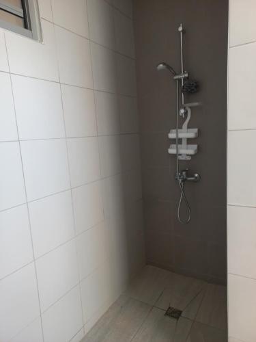 Un baño con ducha con azulejos blancos. en Vaea's Place, en Papeete