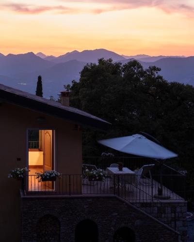a house with a balcony with a table and an umbrella at La Casetta, appartamento con vista lago e montagne in San Zeno di Montagna
