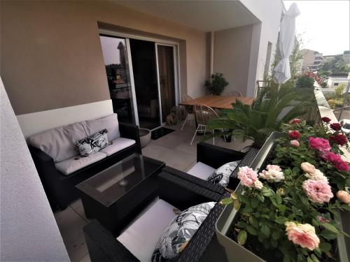 - un salon avec un canapé et des fleurs sur un balcon dans l'établissement Appart 2 chambres climatisé piscine parkings, à Hyères
