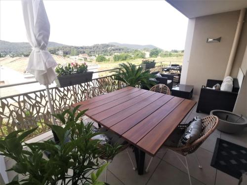 - une table en bois sur le balcon d'une maison dans l'établissement Appart 2 chambres climatisé piscine parkings, à Hyères