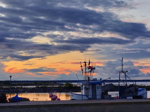 a boat is docked in the water with a sunset at Susanne's stugor Böda hamn in Böda