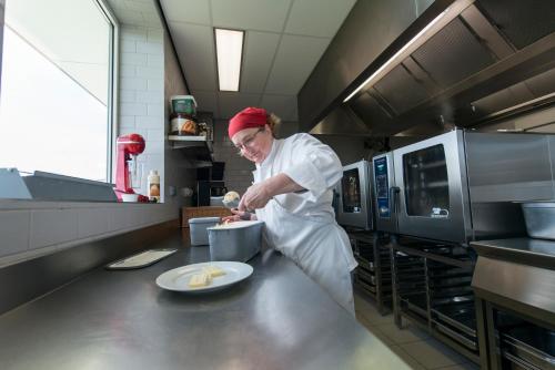 a woman is preparing food in a kitchen at Hotel Middelpunt - Gratis Parking - Ontbijt inbegrepen - in Middelkerke