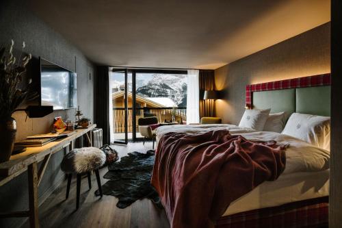 a bedroom with a bed and a desk and a window at Bergwelt Grindelwald - Alpine Design Resort in Grindelwald