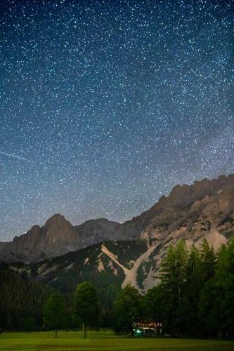 a star filled night sky with a field and mountains at Apartman Ramsau in Ramsau am Dachstein