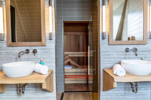 two sinks in a bathroom with a person sleeping in the shower at Just Texel Suites & Apartments in Den Burg