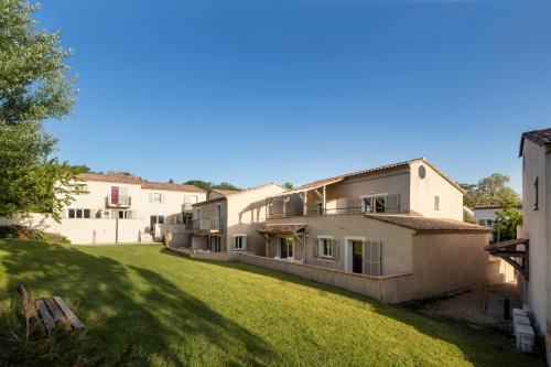a row of buildings in a yard with a green lawn at Garden & City Mont-Ventoux Malaucène in Malaucène