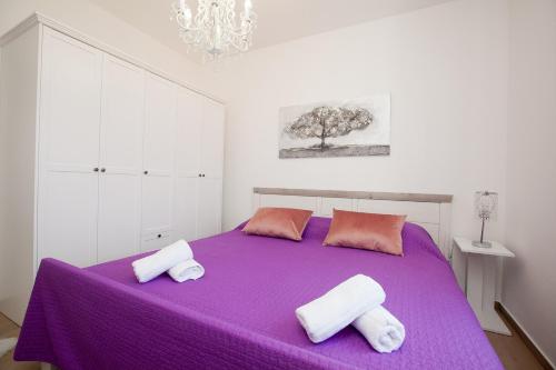 a white bedroom with a purple bed with two towels at Luxury apartment Eva in Zadar