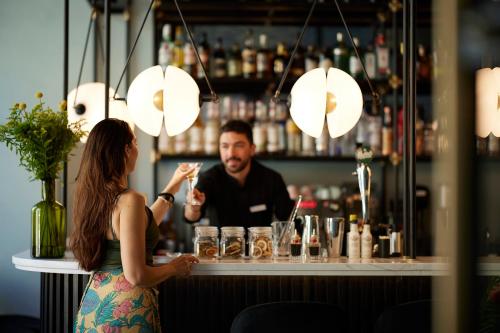 a woman standing at a bar with a bartender at The Port Square Hotel in Piraeus