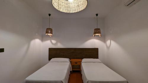 two beds in a small room with two lights at Hotel de Montaña La Hortizuela in Coto Rios