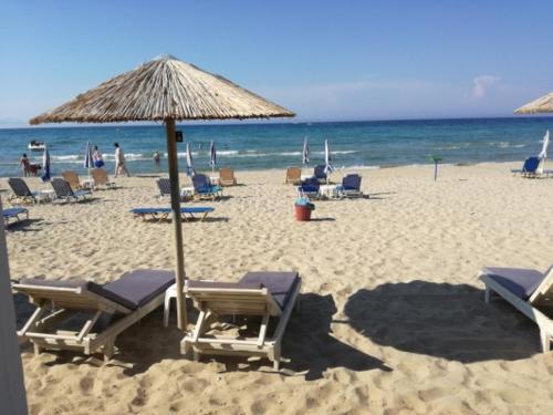 a beach with chairs and an umbrella and the ocean at Casa Dyonisia Tsilivi in Plános