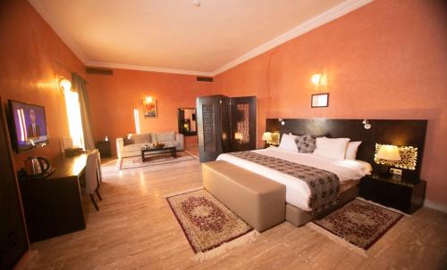 a bedroom with a large bed and a living room at Palais Du Desert Hotel & Spa in Erfoud