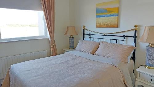 a bed in a bedroom with a window and a bedspread at Southland Holiday Home by Trident Holiday Homes in Miltown Malbay