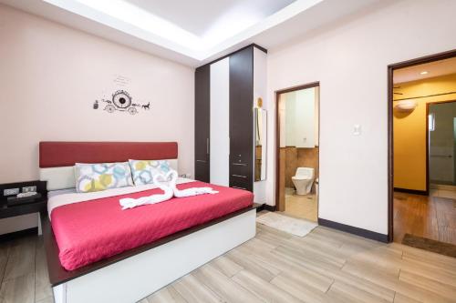 a bedroom with a red bed and a bathroom at Casa Heradurra Uno/Dos in Manila