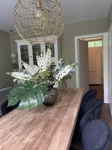 a vase with white flowers on a wooden table at Comfortabel tot rust komen in het Veluwse bos in Otterlo