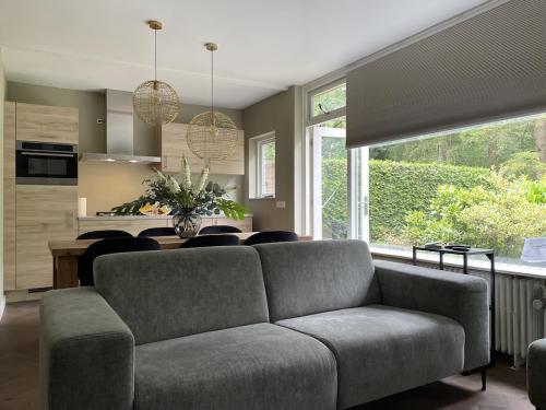 a living room with a couch and a kitchen at Comfortabel tot rust komen in het Veluwse bos in Otterlo